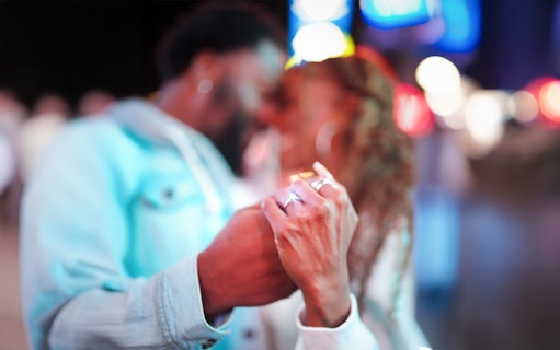 Couple holding hands with engagement ring visible during proposal.