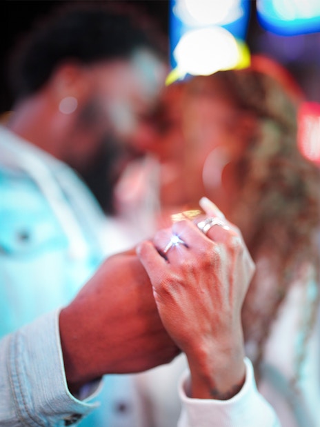 Couple holding hands with engagement ring visible during proposal.