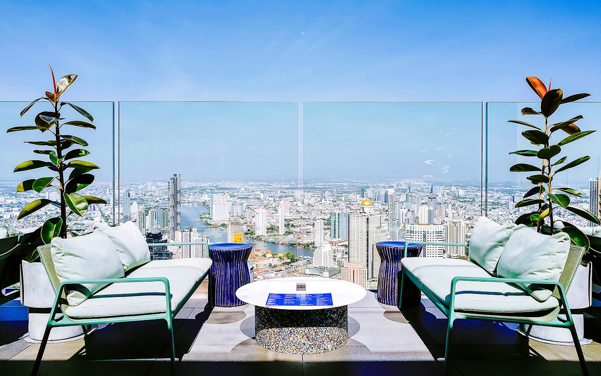 Rooftop seating area overlooking Bangkok skyline from Mahanakhon SkyWalk, Thailand.