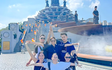 Group posing in front of Cao Dai Holy See, Tay Ninh, with statues and flags visible.