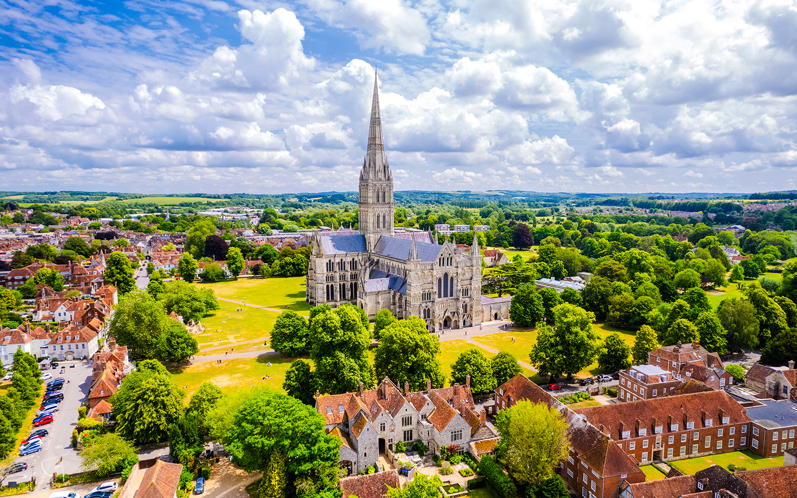 Aerial view of Salisbury Cathedral surrounded by lush greenery and historic buildings.