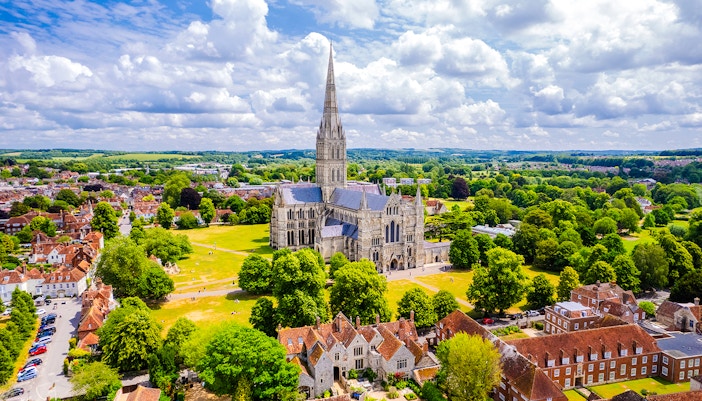 Aerial view of Salisbury Cathedral surrounded by lush greenery and historic buildings.