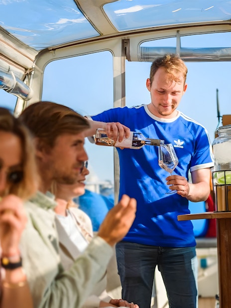 Server pouring drinks on a canal cruise in Amsterdam's Red Light District.
