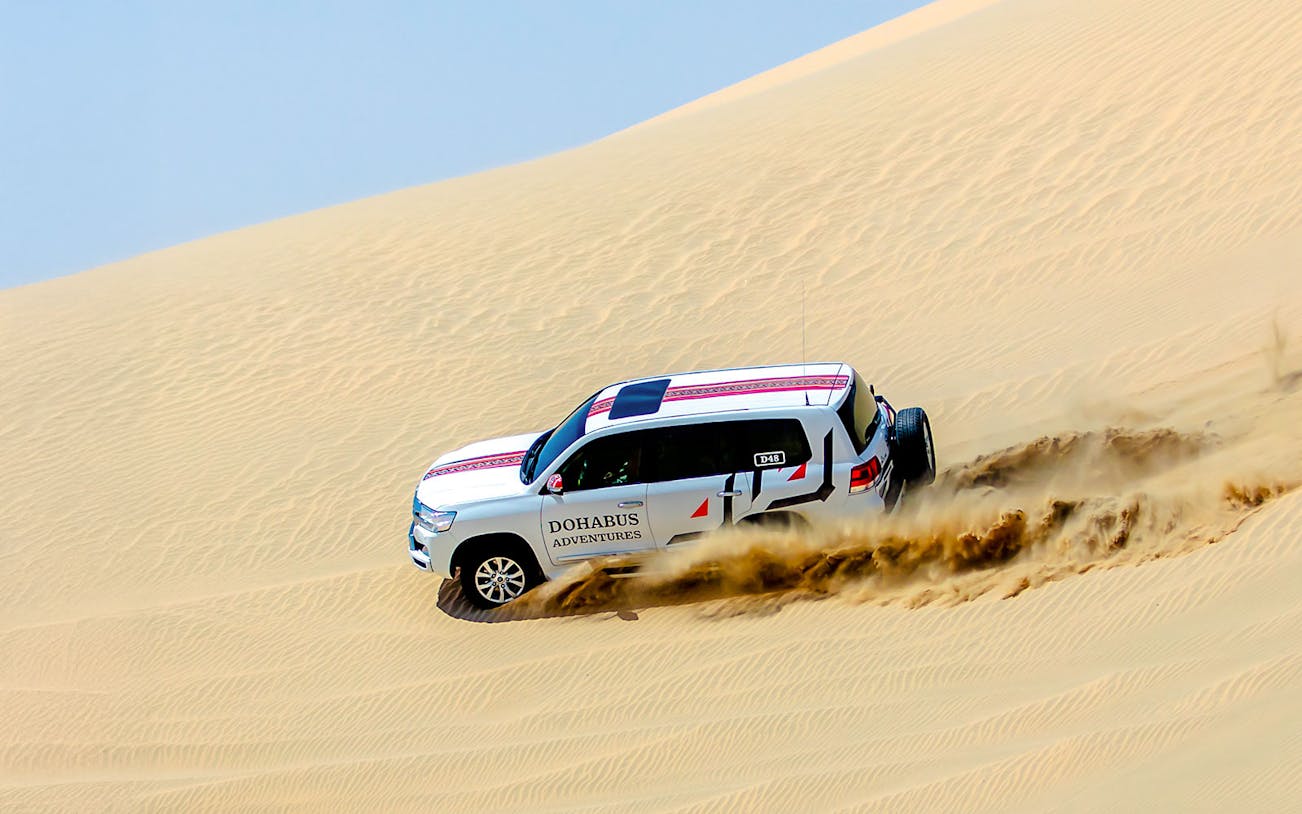 SUV driving through sand dunes on a half-day desert safari.
