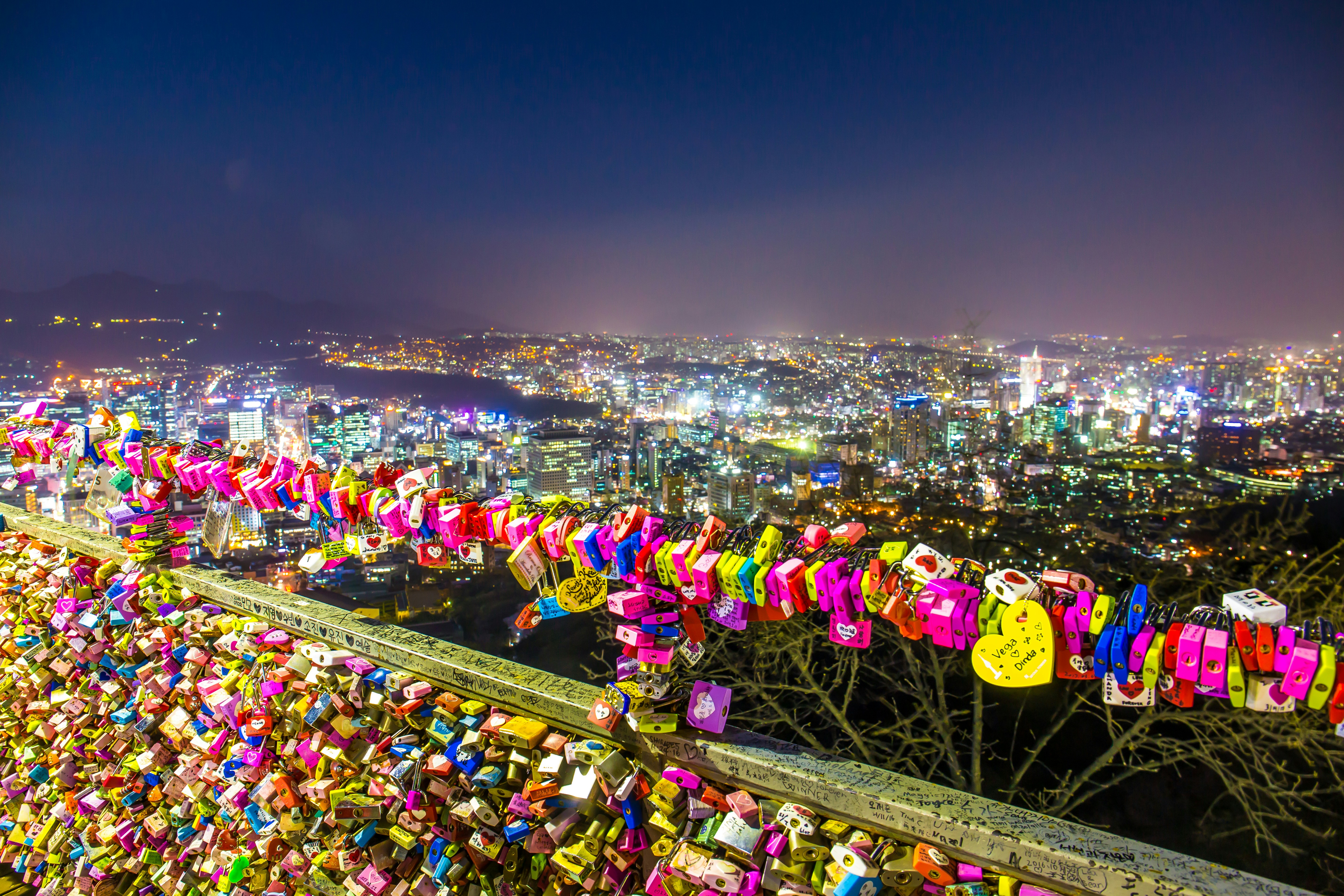 Love locks at N Seoul Tower overlooking Seoul city lights on Namsan Mountain.