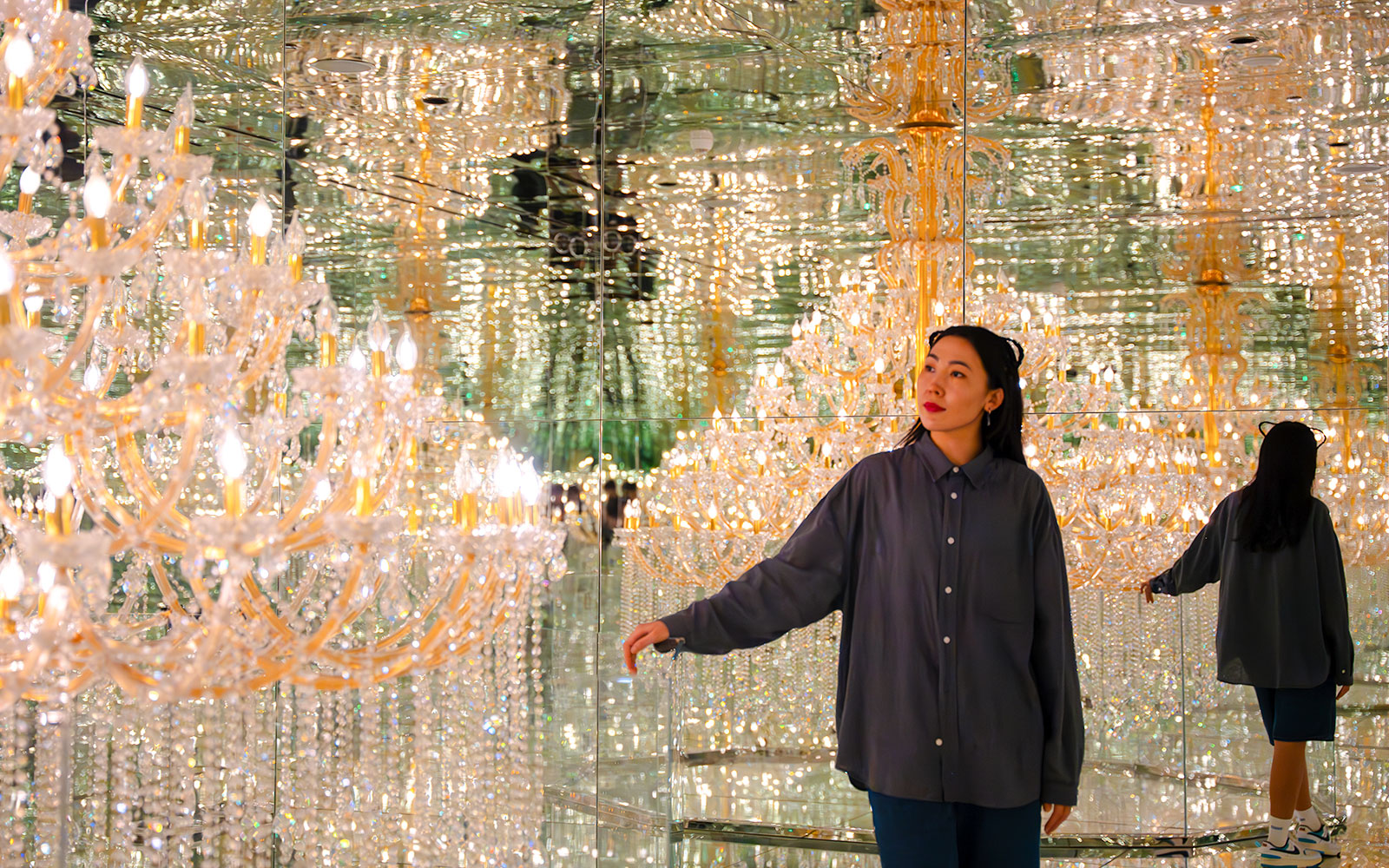 Tourist exploring mirrored room with chandeliers at House of Hype, Dubai.