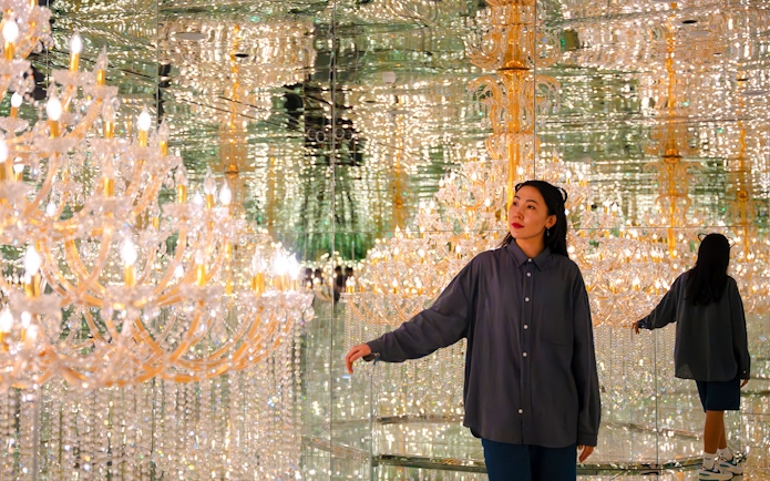 Tourist exploring mirrored room with chandeliers at House of Hype, Dubai.