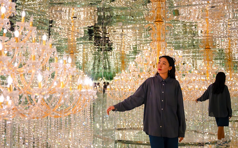 Tourist exploring mirrored room with chandeliers at House of Hype, Dubai.