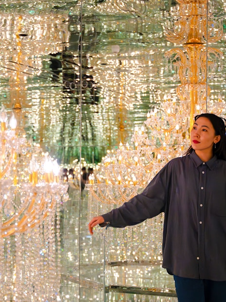 Tourist exploring mirrored room with chandeliers at House of Hype, Dubai.