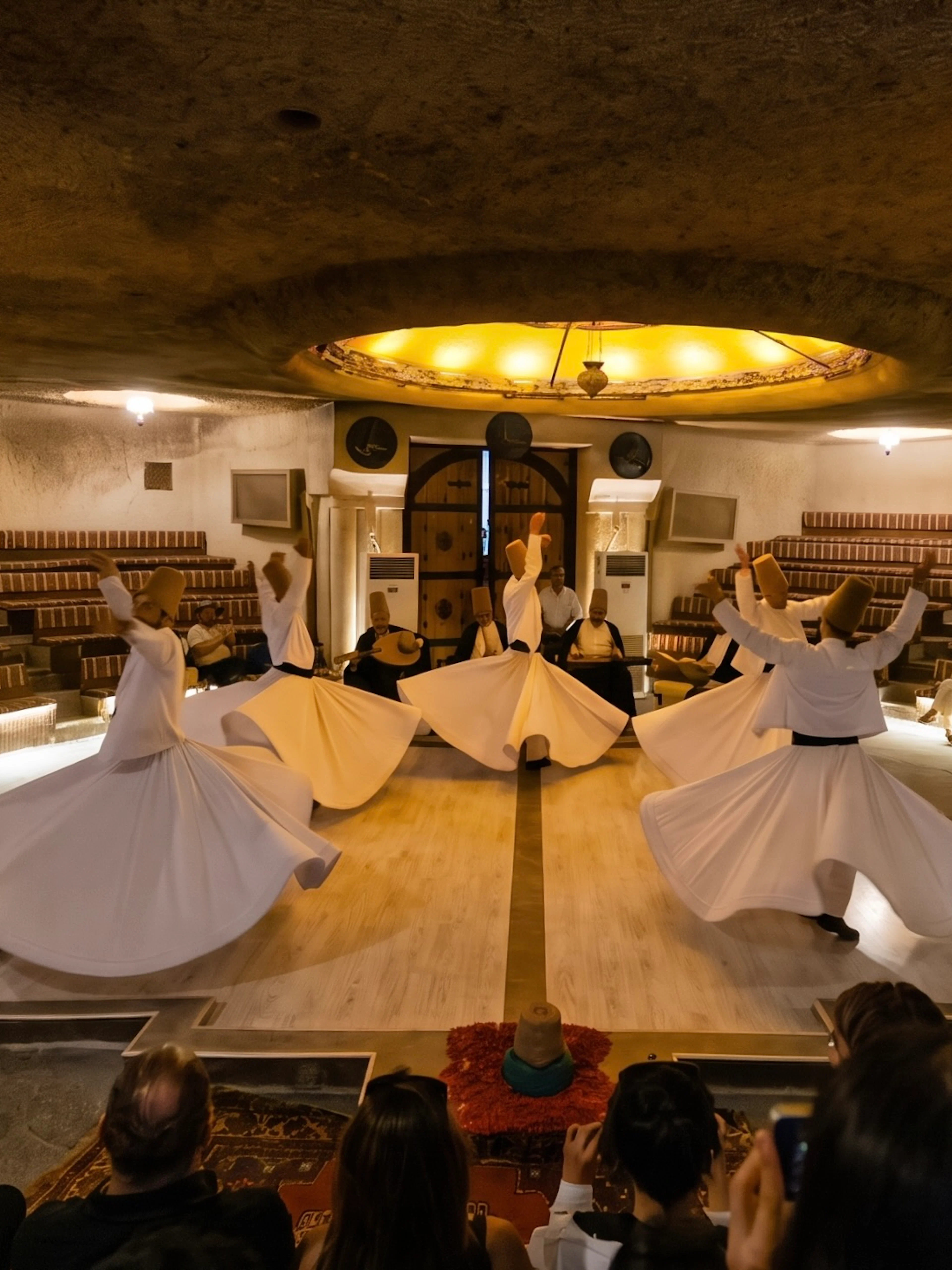 Whirling Dervishes performing Sema Ceremony in a traditional setting with audience.