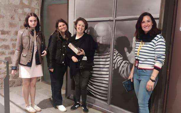 Tourists with guide at Picasso Museum, standing by a large photo of Picasso.