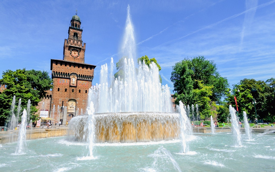 Fountain in front of Sforza Castle, Milan, with clear blue sky.