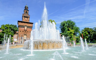 Fountain in front of Sforza Castle, Milan, with clear blue sky.