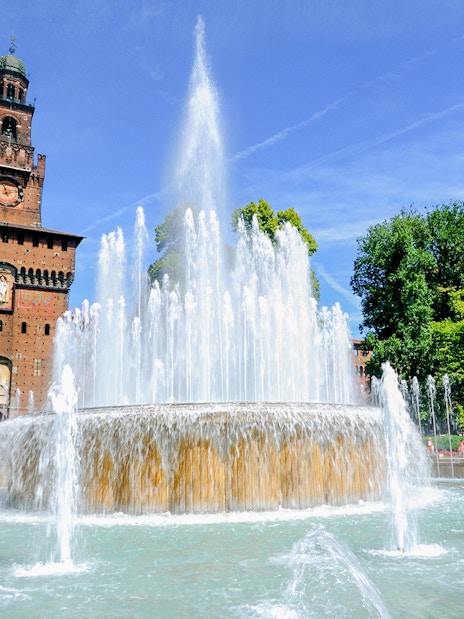 Fountain in front of Sforza Castle, Milan, with clear blue sky.