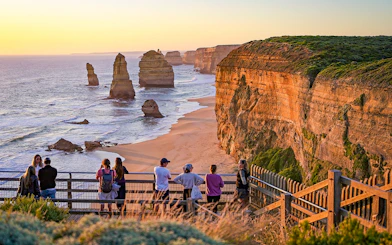 Visitors viewing the Twelve Apostles rock formations along the Great Ocean Road at sunset.