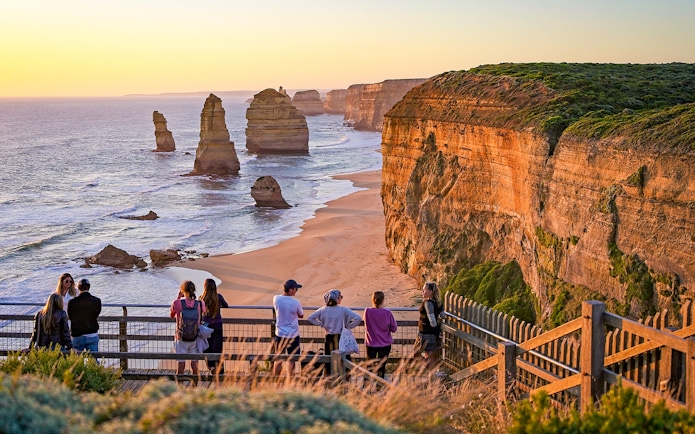 Visitors viewing the Twelve Apostles rock formations along the Great Ocean Road at sunset.