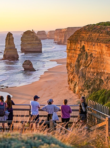 Visitors viewing the Twelve Apostles rock formations along the Great Ocean Road at sunset.