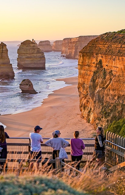 Visitors viewing the Twelve Apostles rock formations along the Great Ocean Road at sunset.