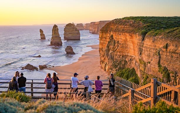 Visitors viewing the Twelve Apostles rock formations along the Great Ocean Road at sunset.