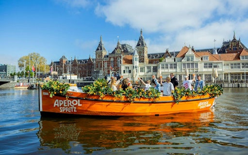 Guests enjoying Aperol Spritz Cruise on a decorated boat in Amsterdam canal.