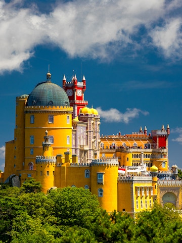 Pena Palace in Sintra, Portugal, with vibrant yellow and red towers against a blue sky.