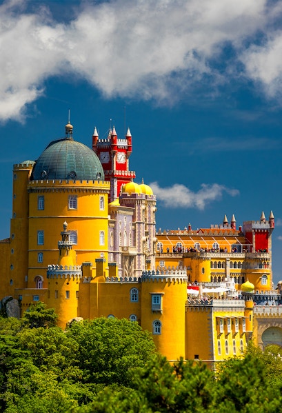 Pena Palace in Sintra, Portugal, with vibrant yellow and red towers against a blue sky.