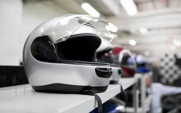 Gokarting helmets lined up on a shelf in an indoor facility.