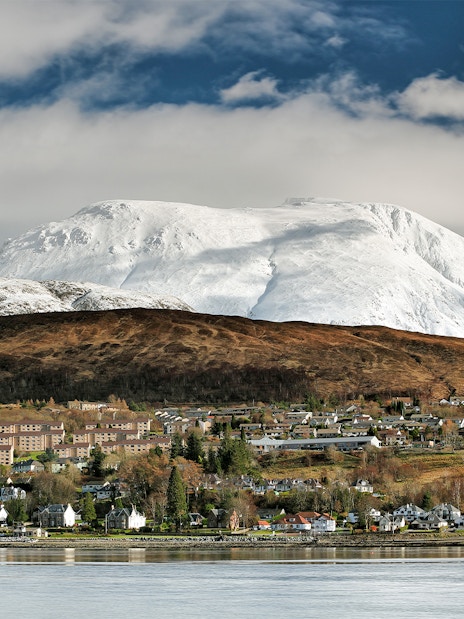 Fort William town with snow-covered Ben Nevis in the background during winter.