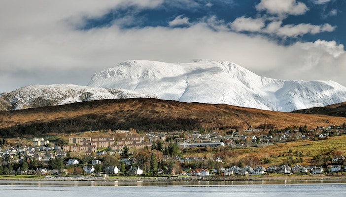 Fort William town with snow-covered Ben Nevis in the background during winter.