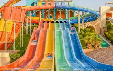 Colorful water slides at Makadi Water World Aqua Park, Hurghada, with people enjoying rides.