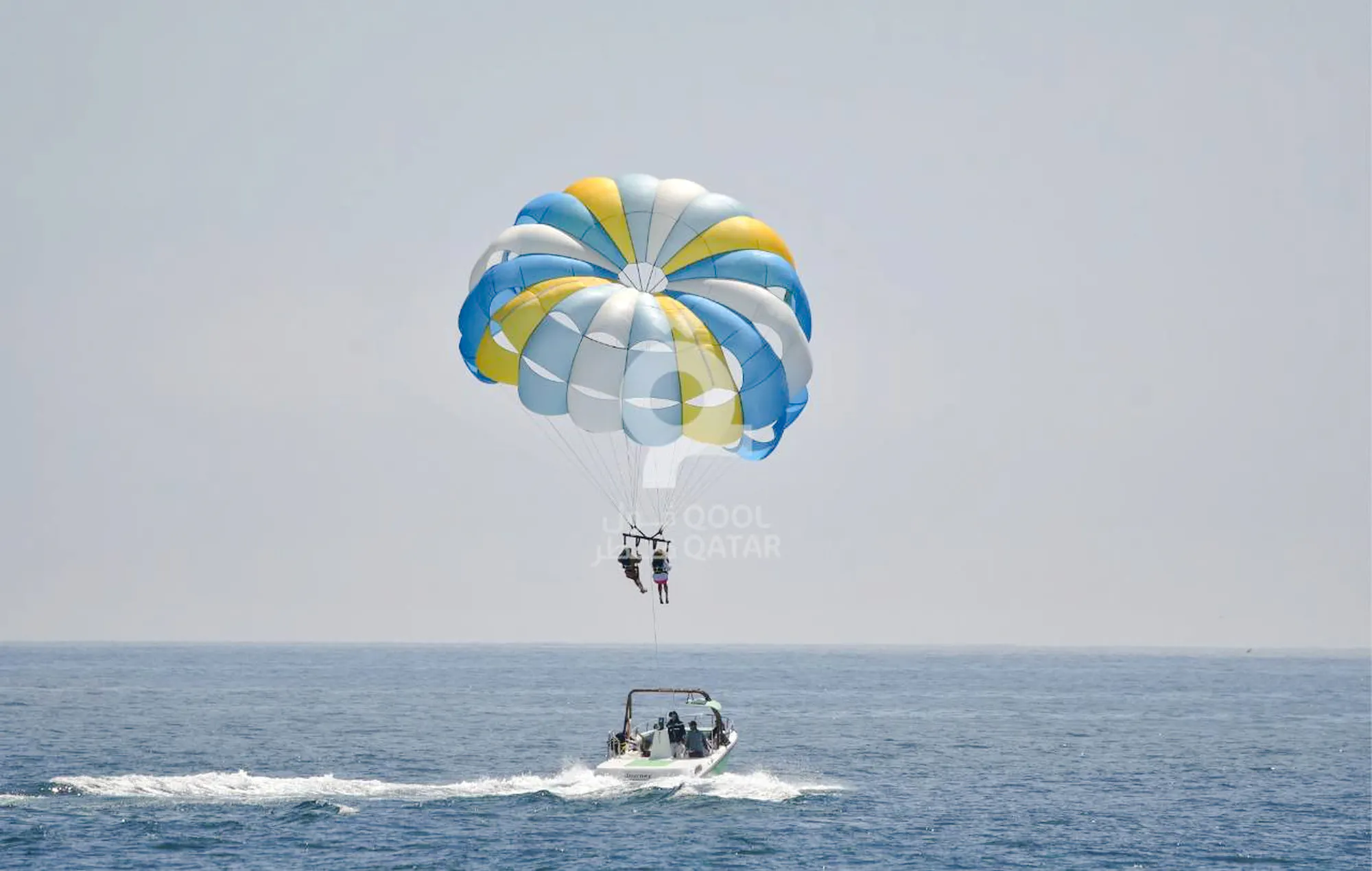 Parasailing over the sea in Doha, Qatar with a colorful parachute.