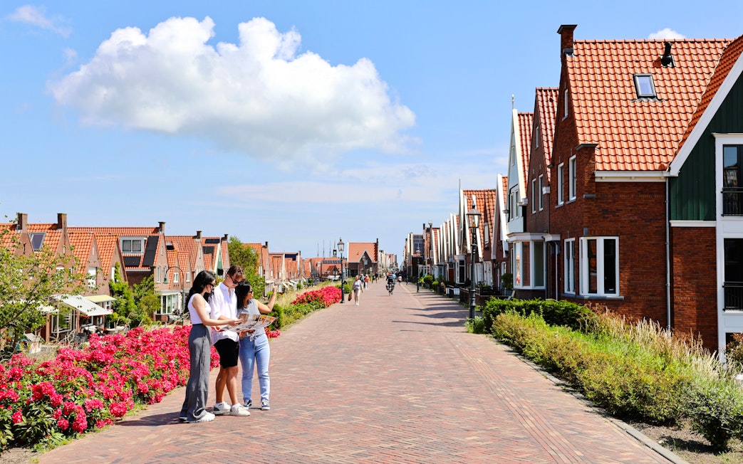 Tourists exploring the picturesque streets of Volendam with traditional Dutch houses.