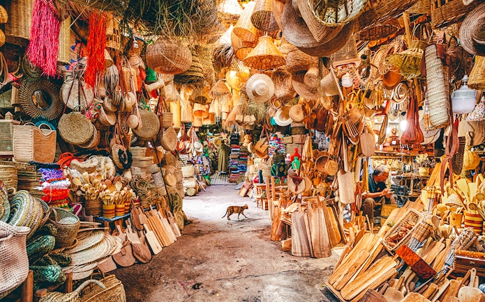 Bustling market stall with woven baskets and wooden crafts in Marrakech souk, Morocco.