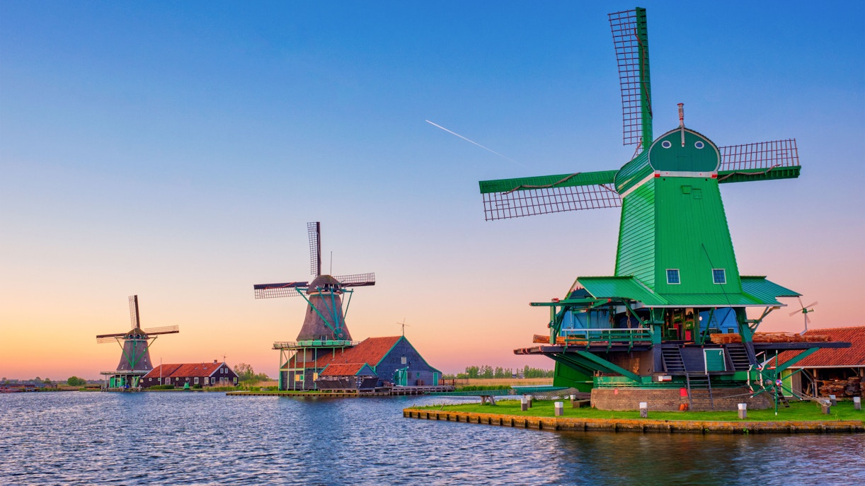 Zaanse Schans windmills by the water at sunset in the Netherlands.