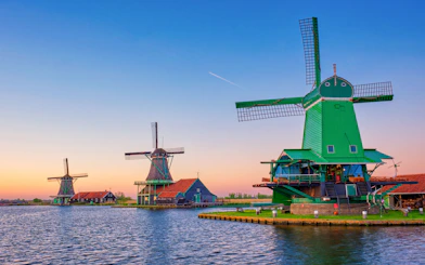 Zaanse Schans windmills by the water at sunset in the Netherlands.