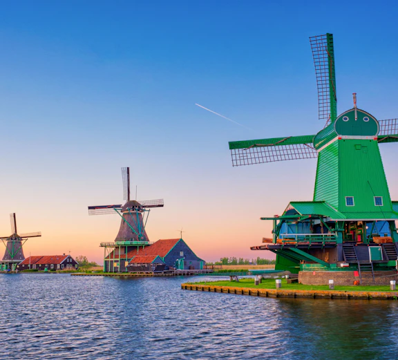 Zaanse Schans windmills by the water at sunset in the Netherlands.