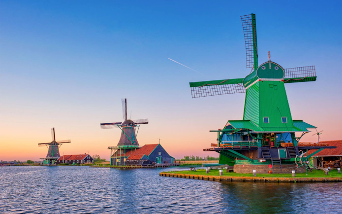 Zaanse Schans windmills by the water at sunset in the Netherlands.