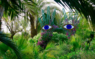 Sculpture with blue eyes among lush greenery at ANIMA Garden.