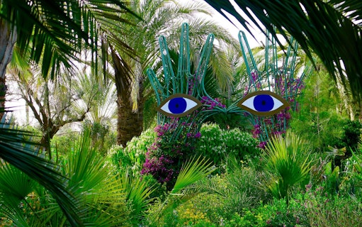 Sculpture with blue eyes among lush greenery at ANIMA Garden.