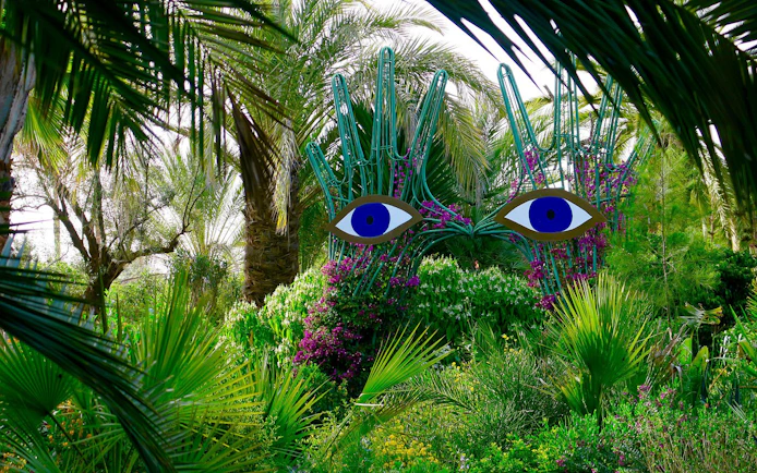 Sculpture with blue eyes among lush greenery at ANIMA Garden.