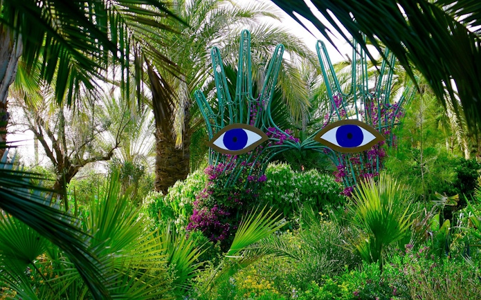 Sculpture with blue eyes among lush greenery at ANIMA Garden.