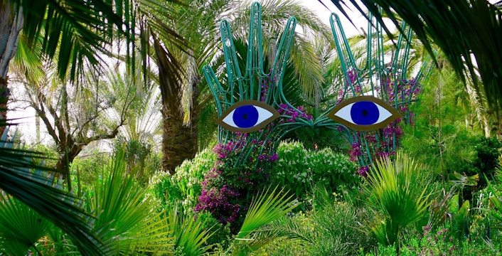 Sculpture with blue eyes among lush greenery at ANIMA Garden.