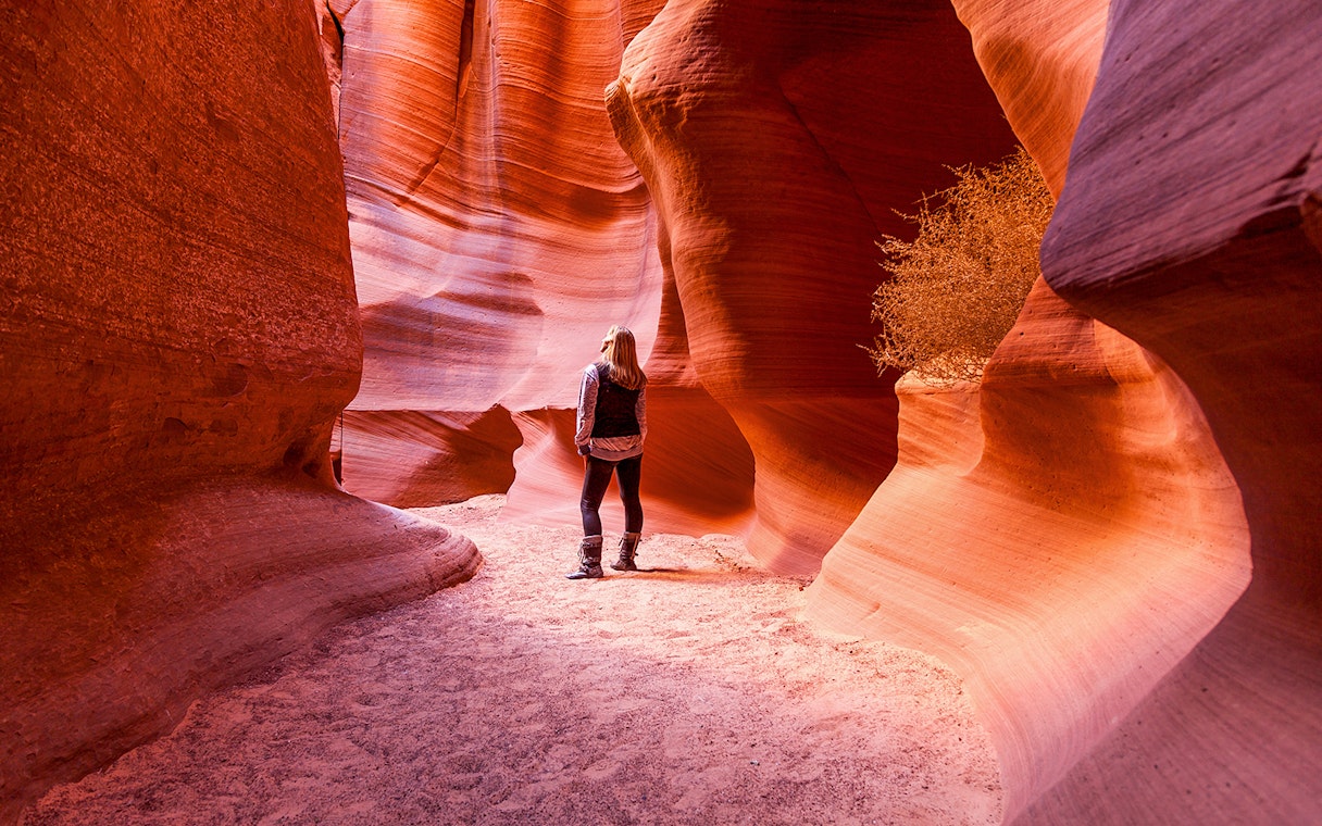 Visitor exploring the narrow sandstone walls of Antelope Canyon X, Arizona.