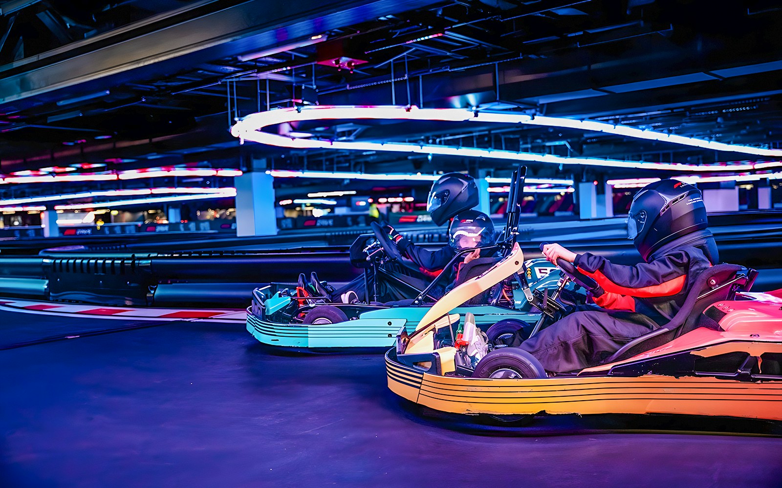 Guests racing go-karts at F1 experience in London indoor track.