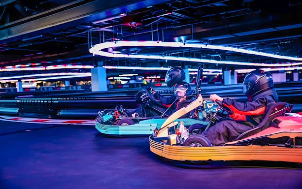 Guests racing go-karts at F1 experience in London indoor track.