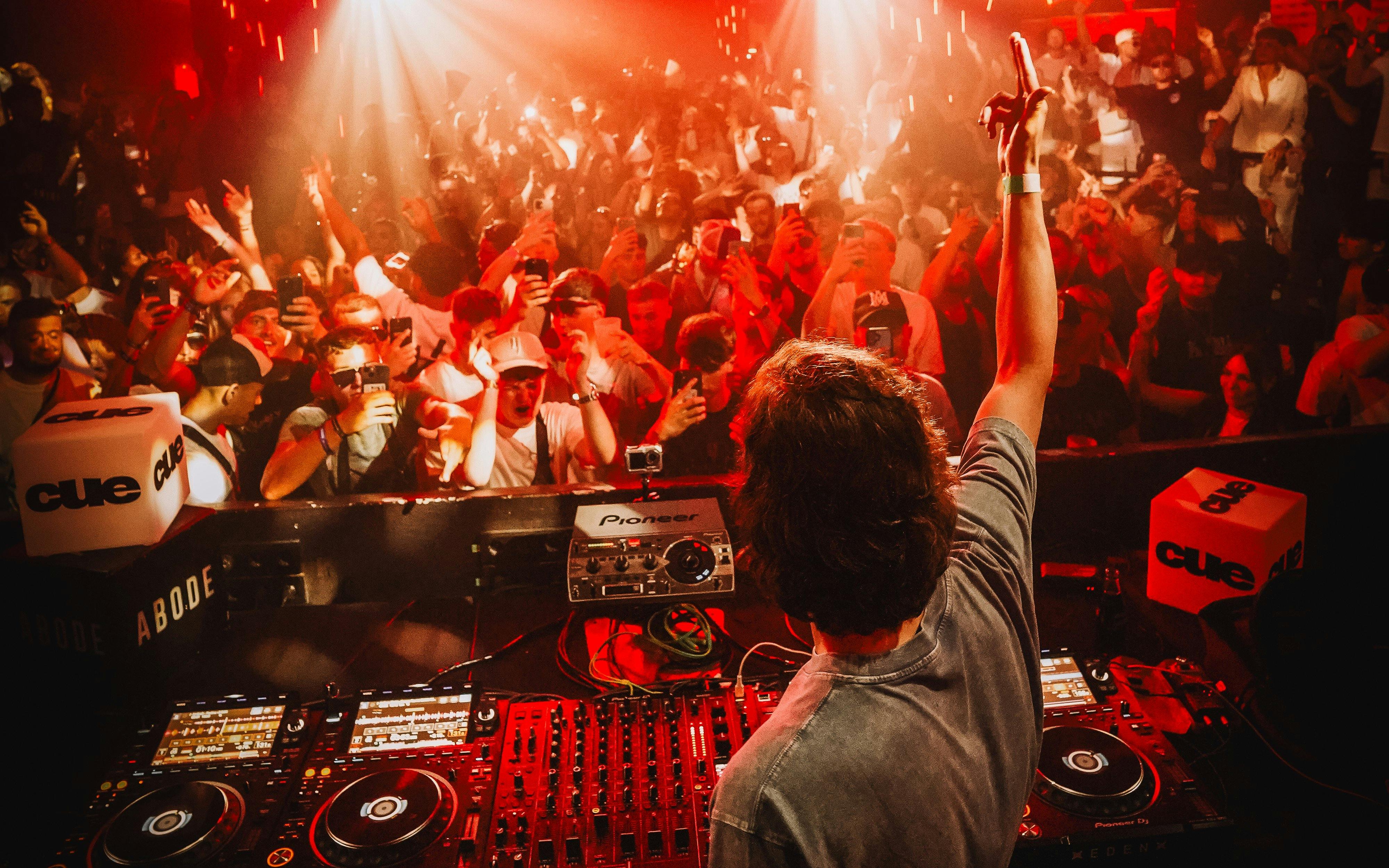 DJ performing at Eden on Sundays CUE Ibiza Party with crowd dancing and lights.