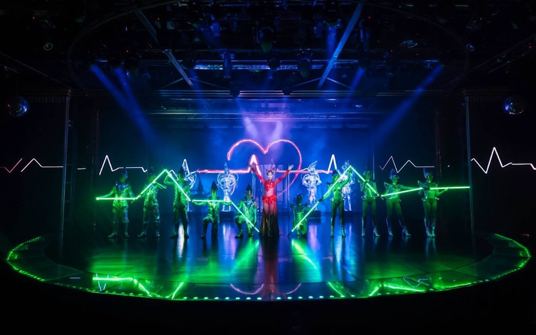 Calypso Cabaret performers with neon lights on stage in Bangkok.