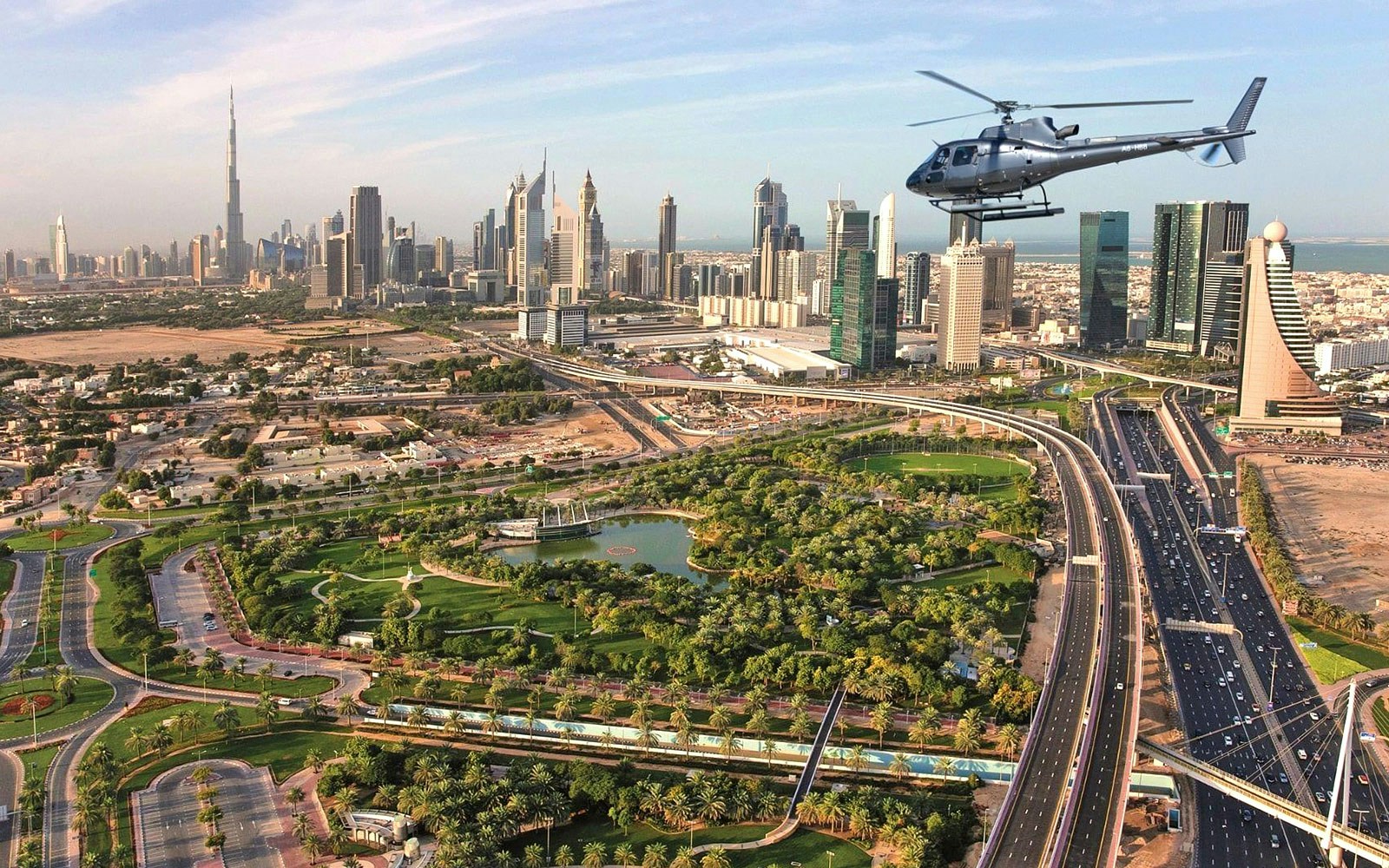 Helicopter flying over Dubai skyline with Burj Khalifa in view.