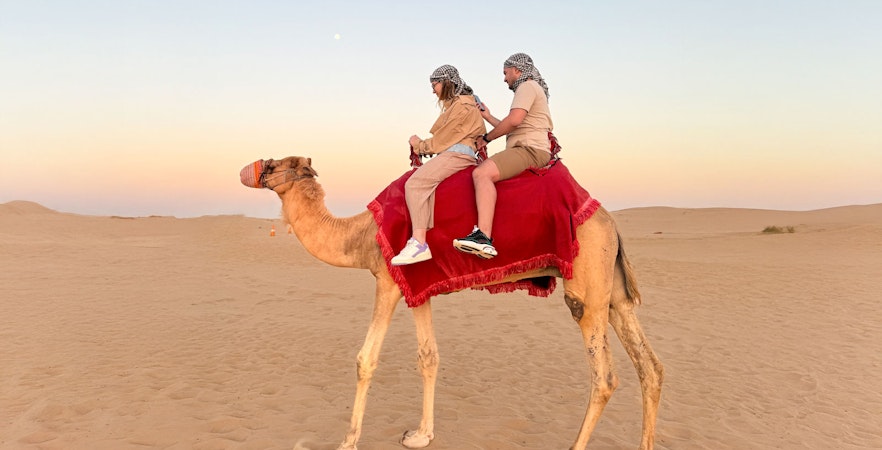 Camel ride during Dubai desert safari at sunset.