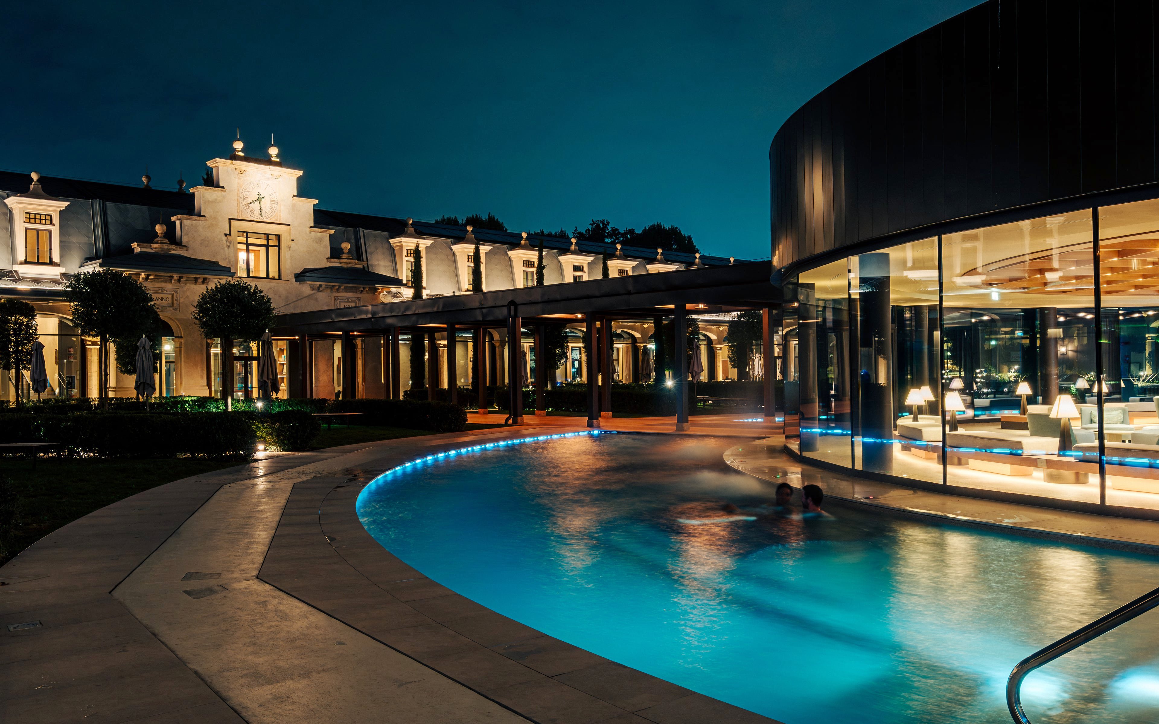 Milan spa with illuminated pool and elegant architecture at night.